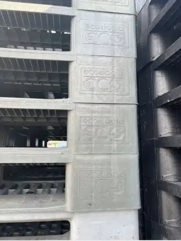 Gestapelte graue Kunststoffpaletten der Marke Ecologic mit geprägtem Logo